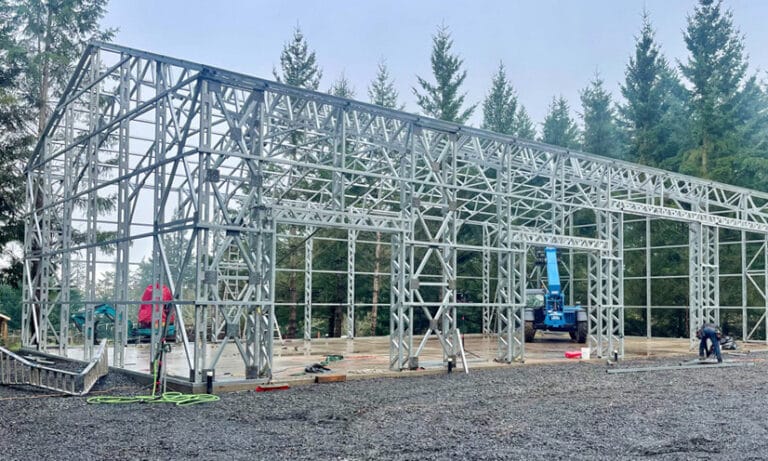 Steel building frame construction in forest setting.