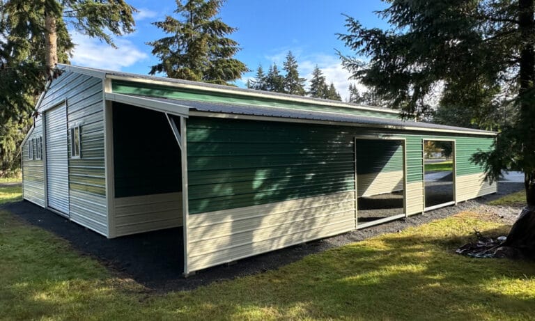 Green and white metal barn in a forested area.