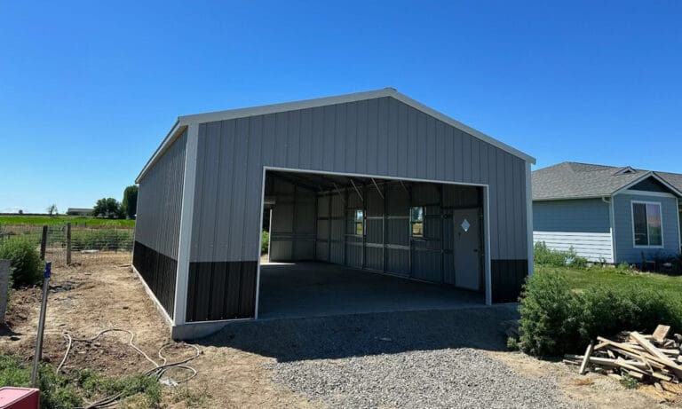 Empty metal garage beside a house on sunny day.