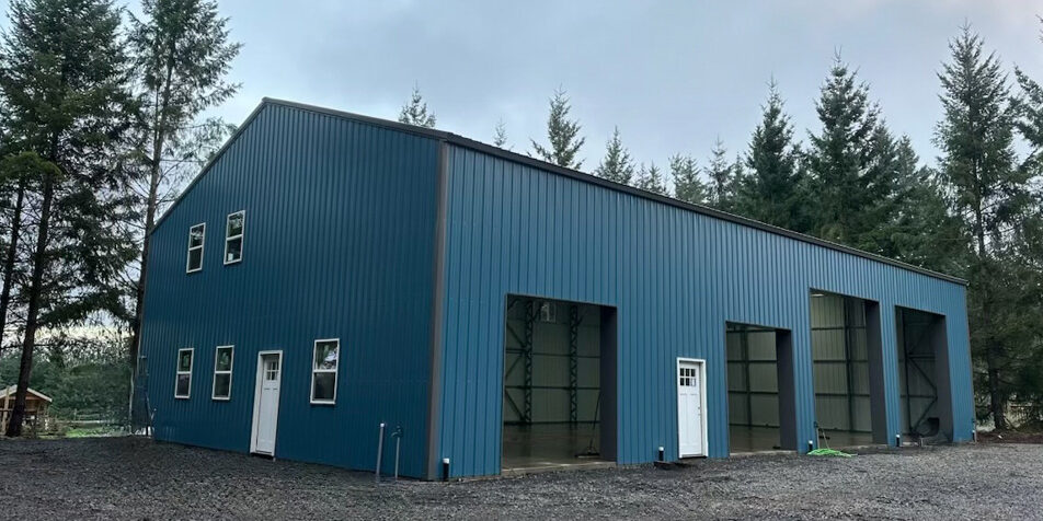 Large blue metal building in wooded area