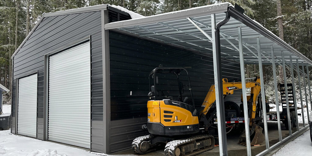 Metal garage with yellow excavators in snow.